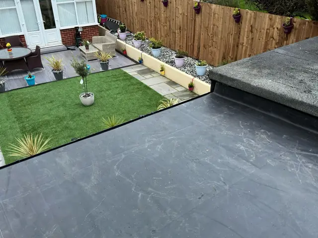 New rubber flat roof on a single-storey extension, looking down over a garden with a lawn, patio and planters